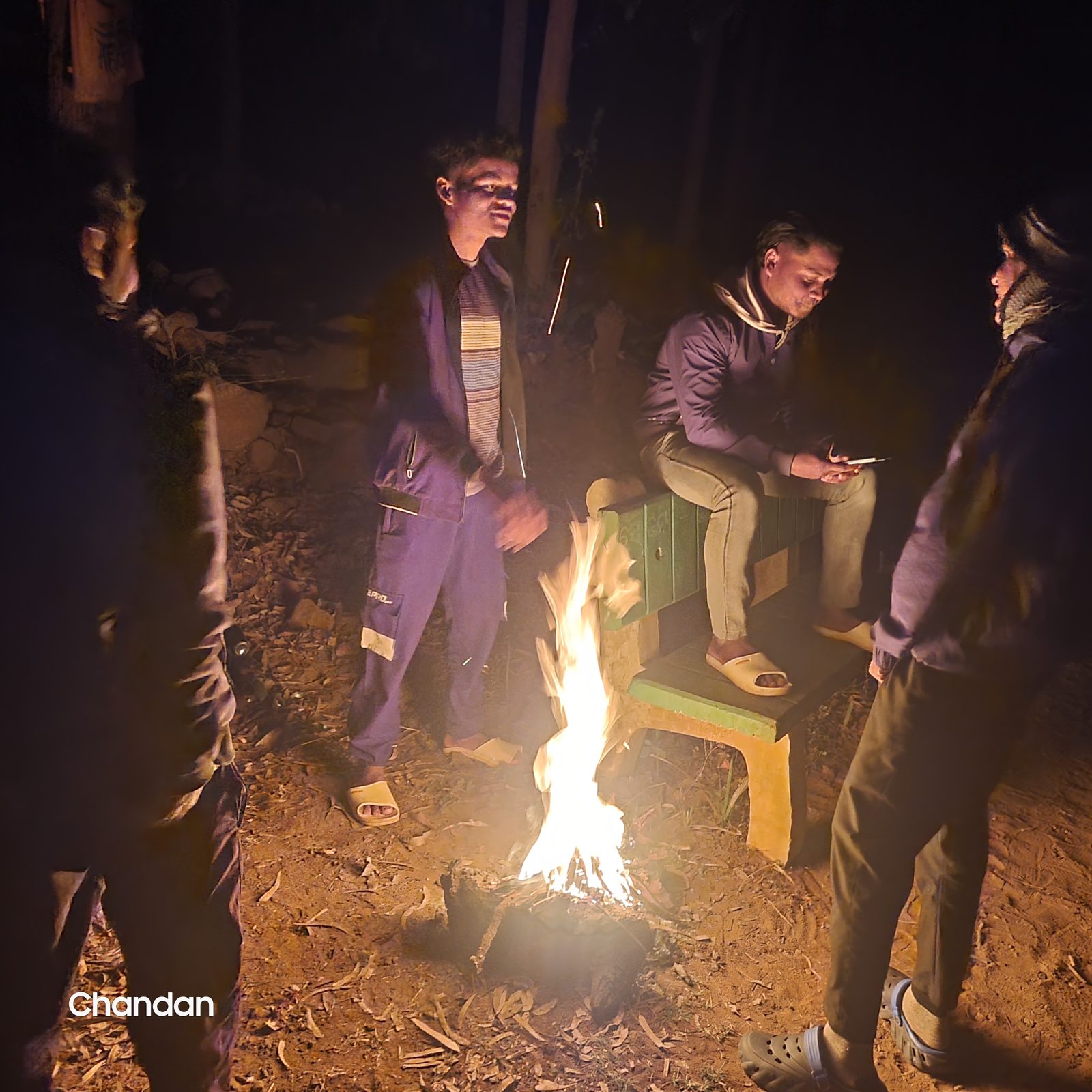 People standing around a fire after dark