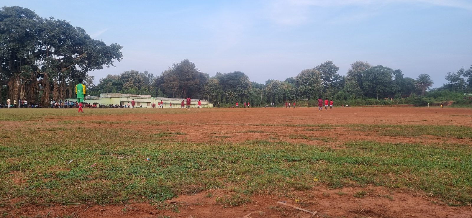 The red earth football ground before a match, trees along the far edge