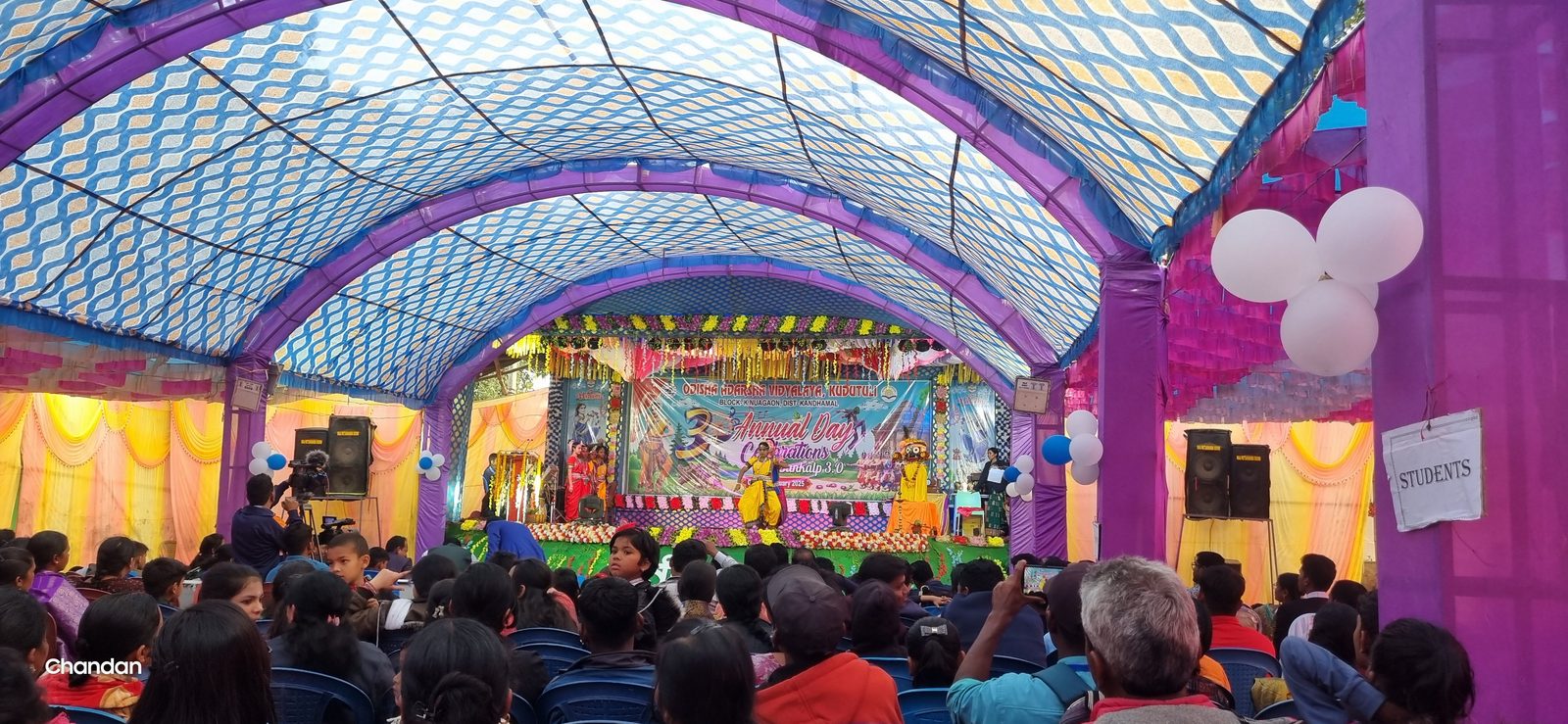 Crowd seated inside a decorated festival pandal