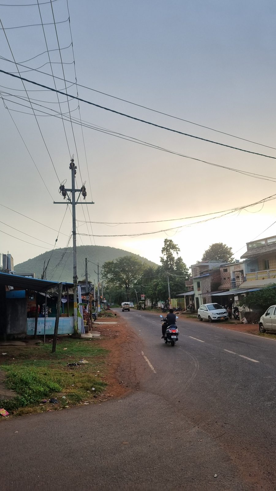 Power lines over the market road at dusk, hills behind