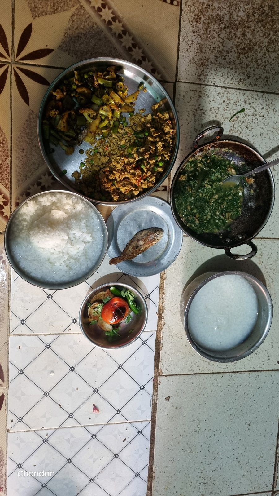 Rice, dal and greens served in steel bowls